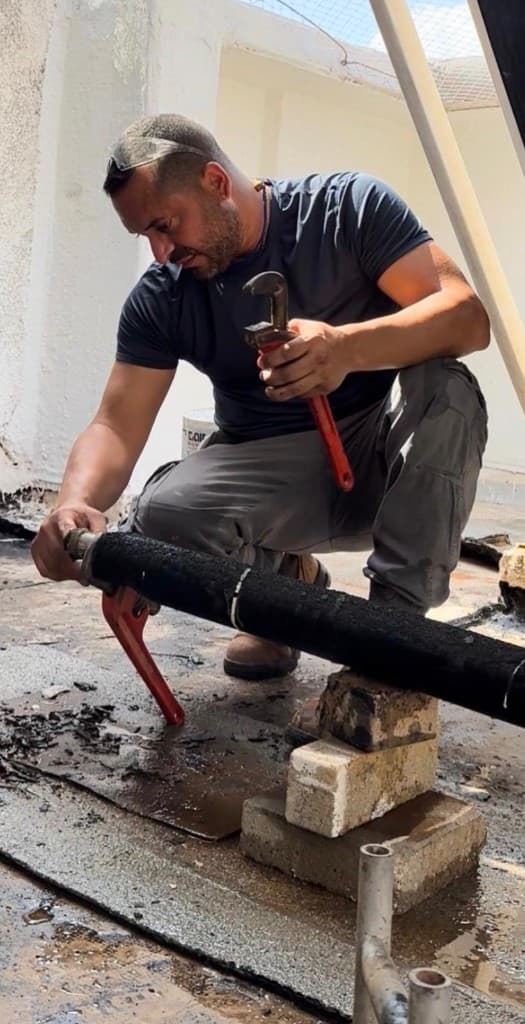 רן שלום מהדק צנרת ראשית עם מפתח צינורות